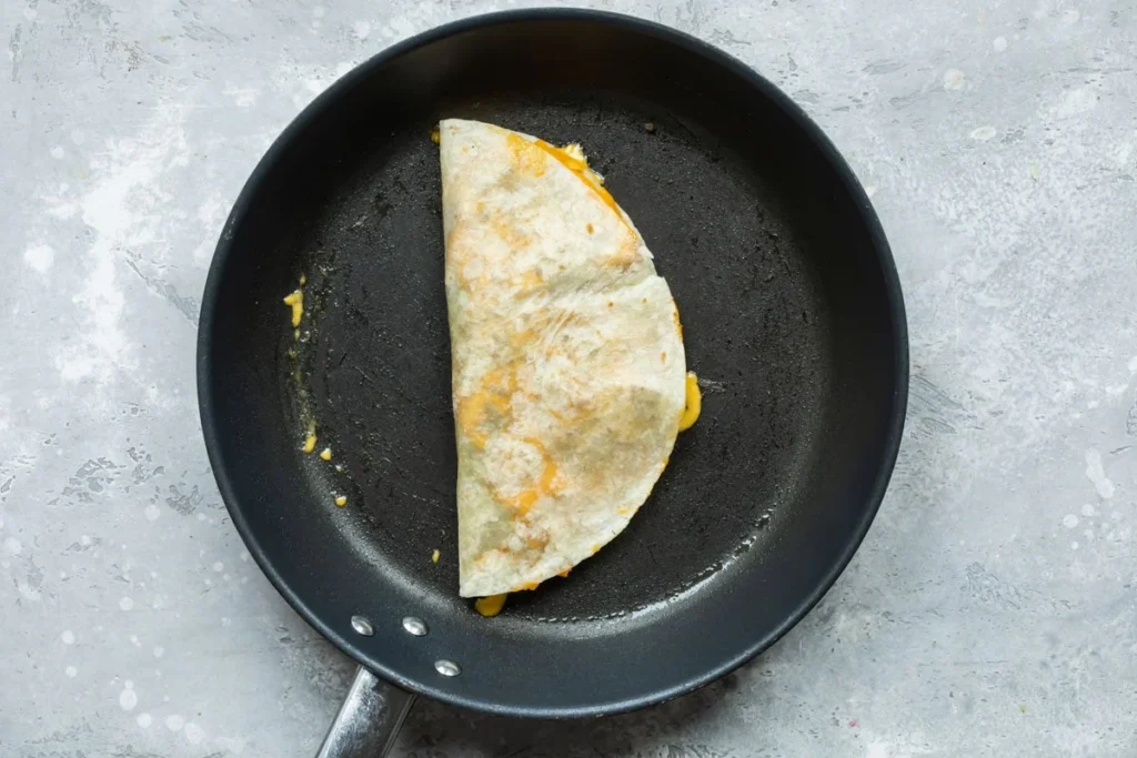 Fold the tortilla in half. Cook for about 2 minutes, until the bottom is golden brown and the cheese starts to melt. Flip carefully and cook until the second side is golden brown and the cheese is fully melted.