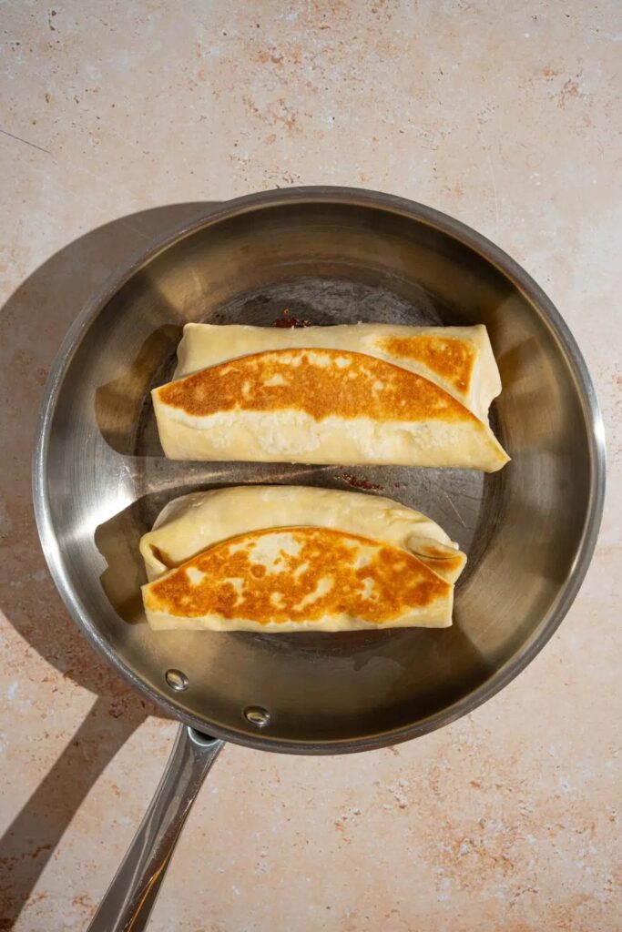 Place the wraps seam-side down in the pan. Cook for 3 to 4 minutes on each side, until golden brown and crispy. Cover the pan with a lid while cooking so the filling warms through.