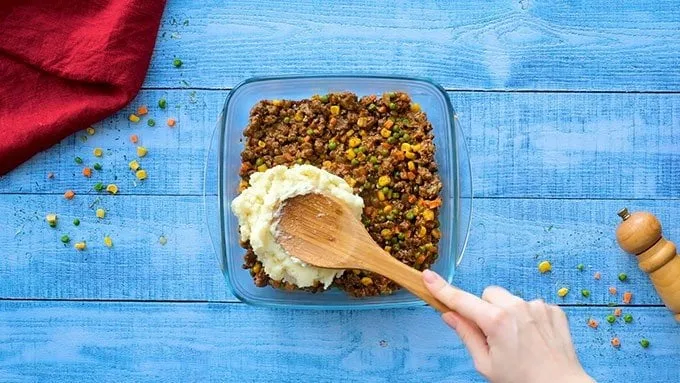 Pour the meat mixture into a 9x9 or 7x11 inch baking dish. Spread it into an even layer. Spoon the mashed potatoes over the top and gently spread them out to cover the meat.