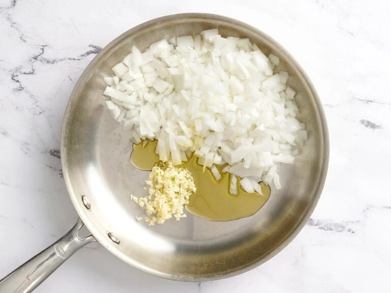 While the pasta cooks, heat olive oil in a large skillet over medium heat. Add the diced onion and garlic and sauté until soft and translucent, about 3–5 minutes.