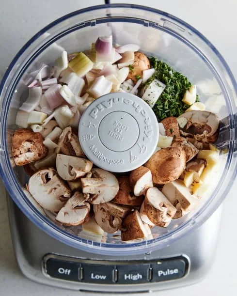 Add the chopped shallots, garlic, thyme, and half of the cremini mushrooms to a food processor fitted with the blade.