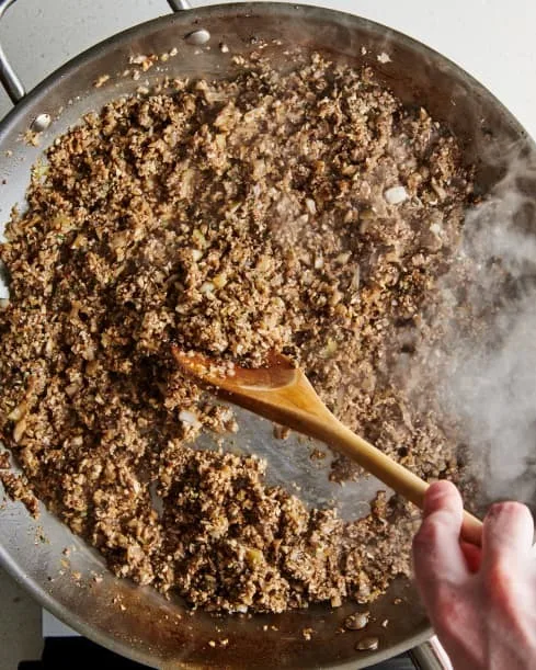 Discard any fat in the pan. Add the butter and return to medium heat. Once melted, add the mushroom mixture and the remaining 1/4 teaspoon kosher salt. Cook, stirring now and then, until the mixture looks dry and starts to brown on the bottom of the pan, about 10 to 20 minutes.