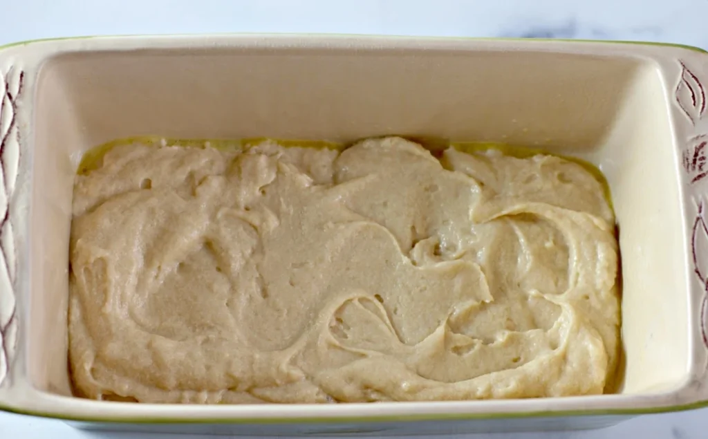 Pour half of the batter into the prepared loaf pan and spread it evenly.