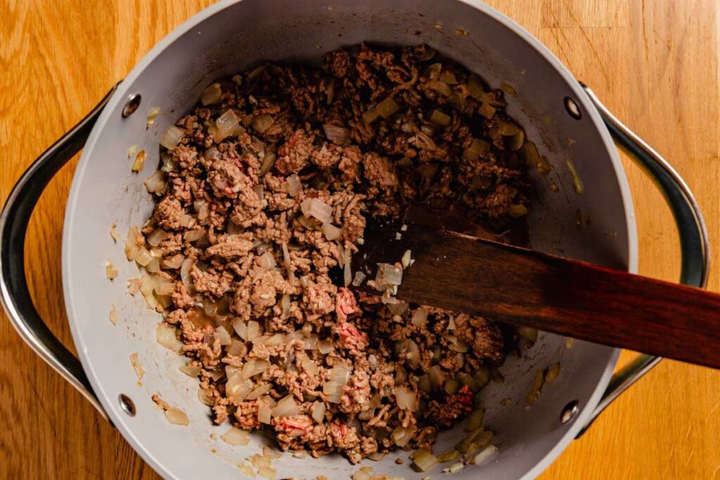 Add the minced garlic, ground beef, and another ¾ teaspoon Morton kosher salt or 1 teaspoon Diamond Crystal kosher salt. Cook for about 4 minutes, breaking up the beef with a wooden spoon, until it is almost cooked through.