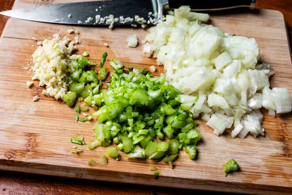 Preheat the oven to 375°F and grease a 9x13 inch casserole dish, then finely chop the onion and celery and mince the garlic so everything is ready to cook.