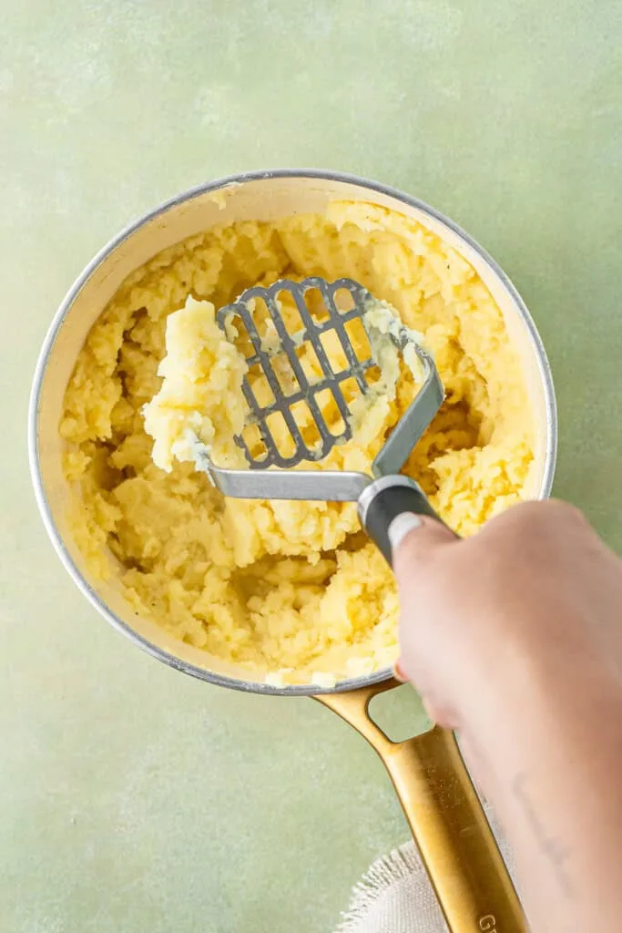Cook the potatoes until soft, then drain completely and mash with butter, salt, pepper, and milk added gradually until smooth and creamy.