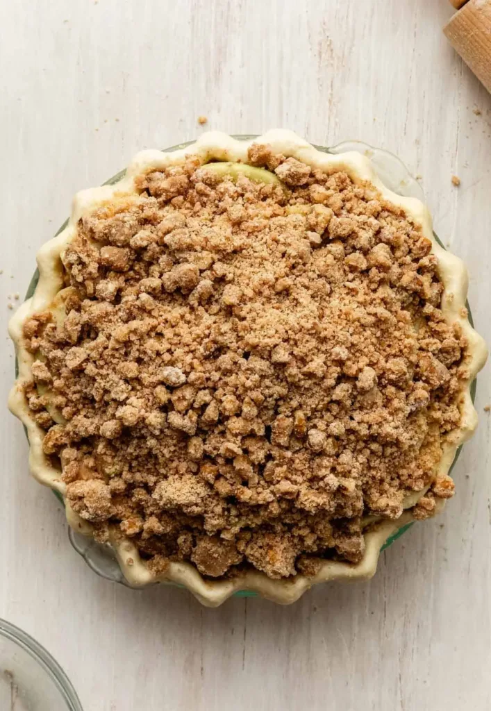 Spoon the apple filling into the prepared crust, spreading it evenly and packing it gently to avoid large gaps between slices.