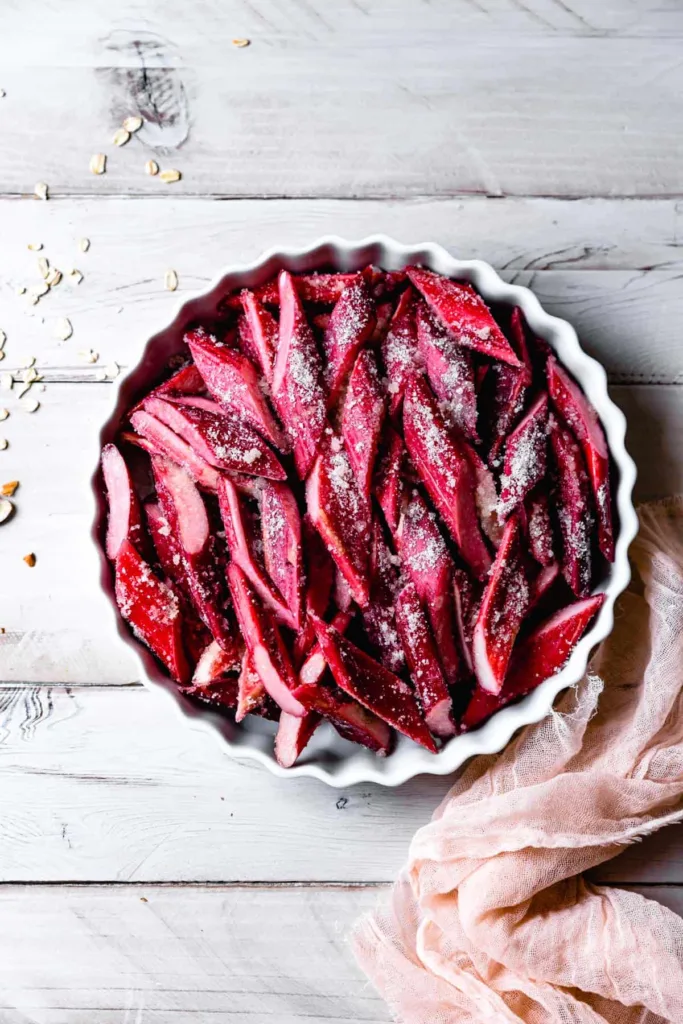 Sprinkle the topping evenly over the baked rhubarb filling, covering the surface without pressing it down too firmly.