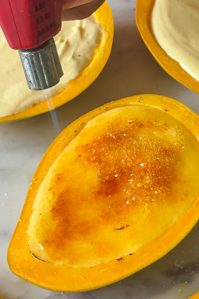 Just before serving, sprinkle a thin, even layer of sugar over the surface and caramelize it using a kitchen torch or hot spoon until golden and crisp, then let it cool briefly before serving.