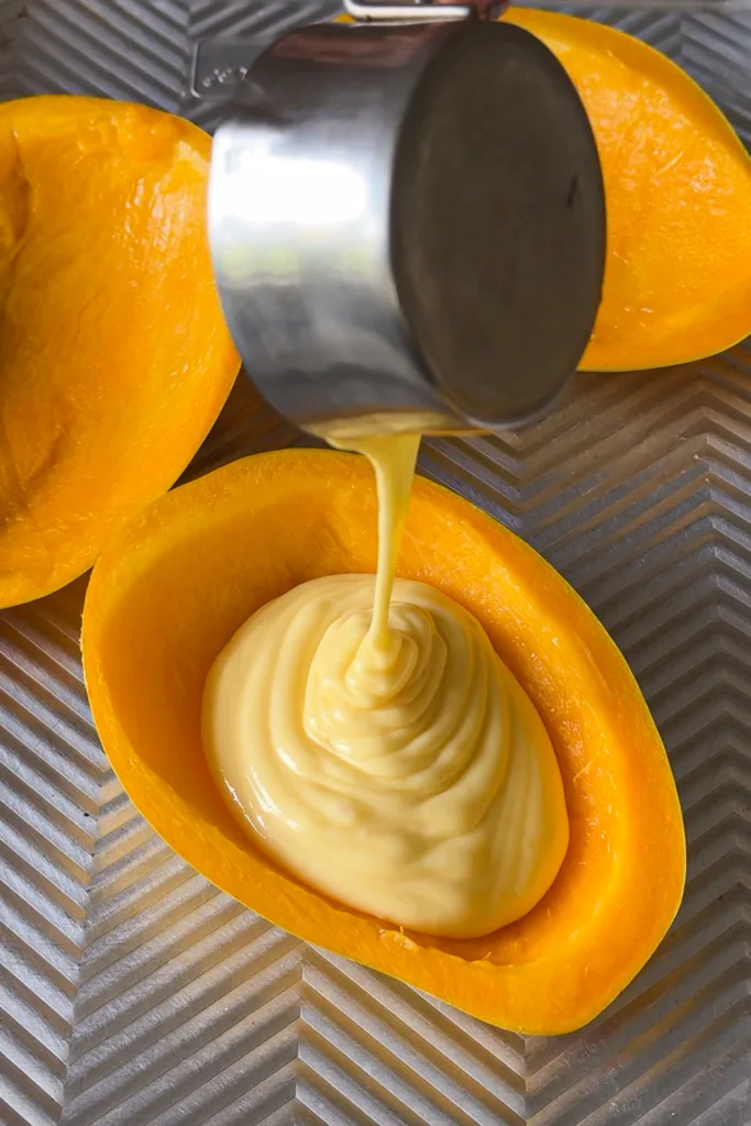 Carefully pour the mixture into the prepared mango peel halves, filling each about three-quarters full to prevent spilling during setting.