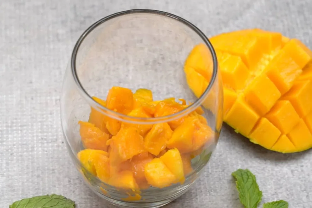 Add chopped mango pieces to serving glasses, then spoon the chia pudding over the top to create a layered effect.