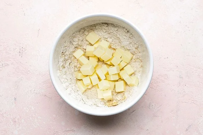 Preheat the oven and mix the flour, oats, and brown sugar in a bowl, then cut in the cold butter until the mixture becomes crumbly.