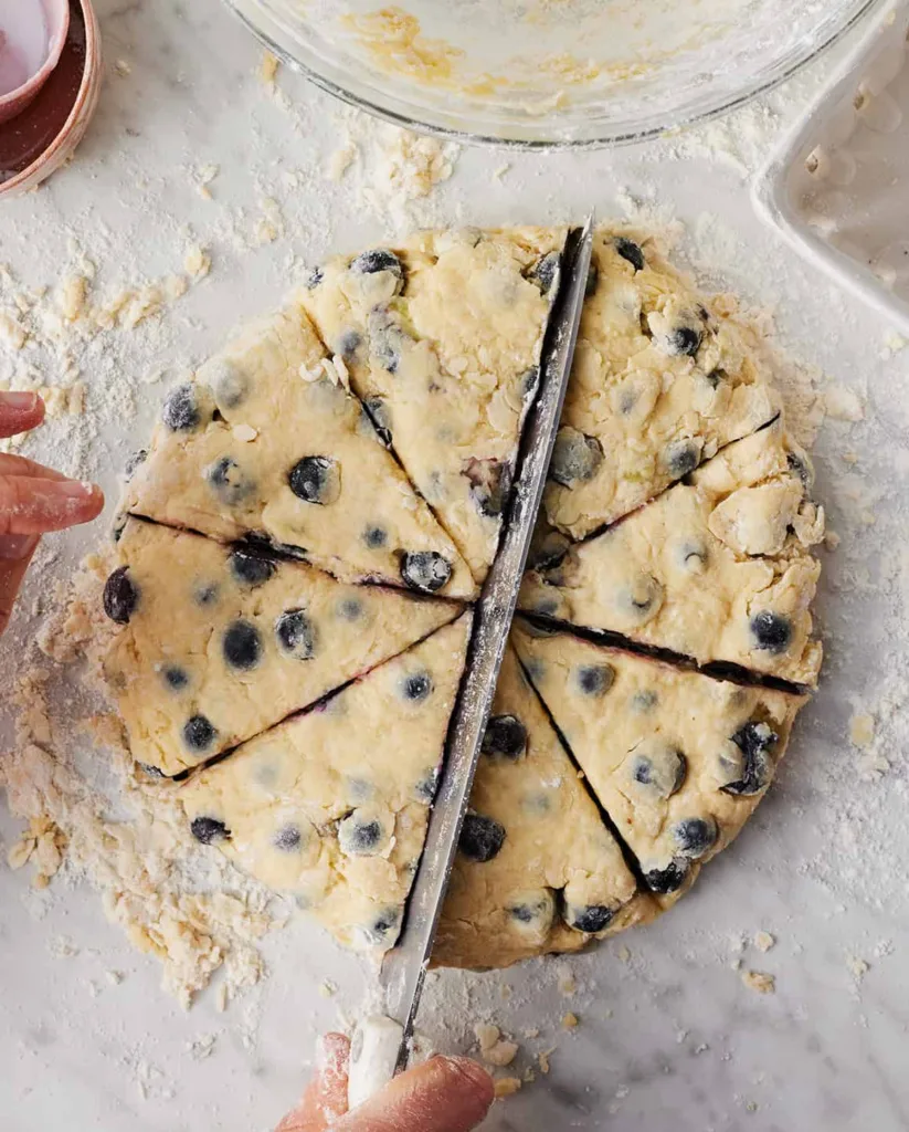 Transfer the dough to a floured surface, shape it into a thick disk, then cut it into equal wedges and place them on the prepared baking sheet.
