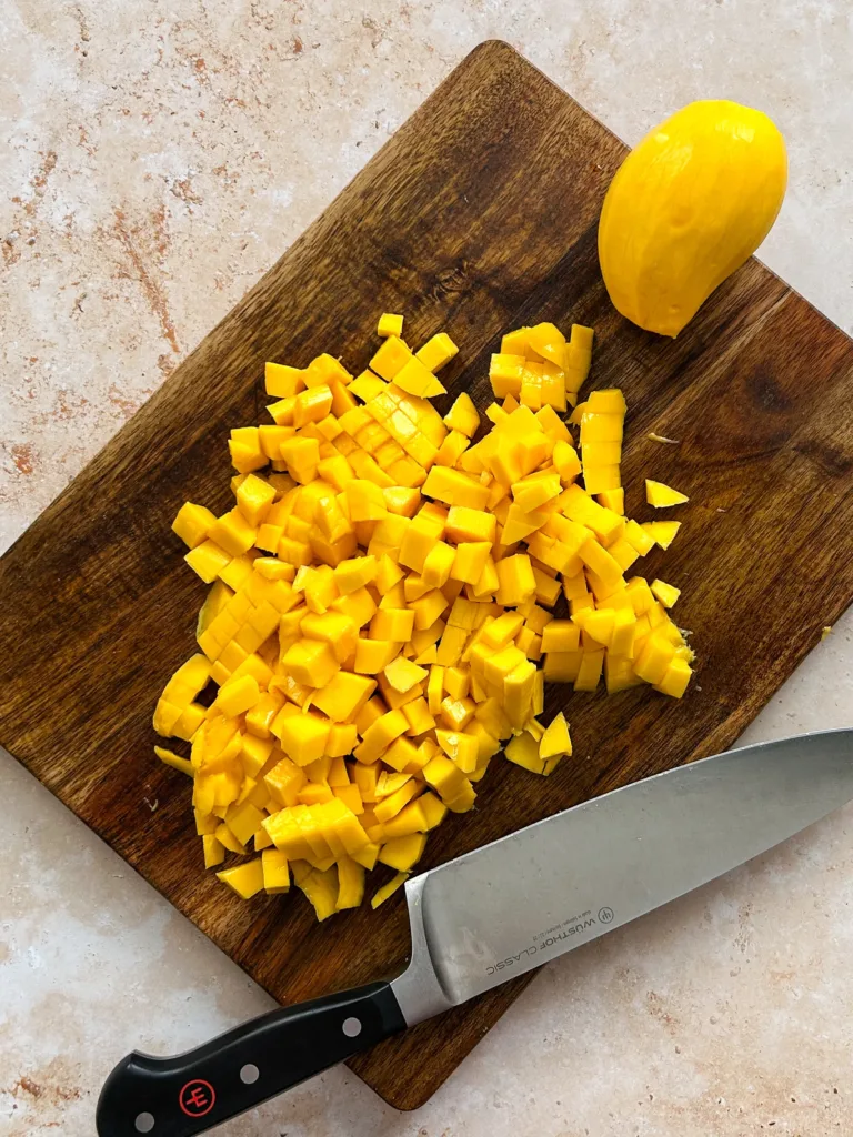 Peel and prepare the mangoes by slicing some thinly for decoration and cutting the rest into small cubes, ensuring they are ready for layering.