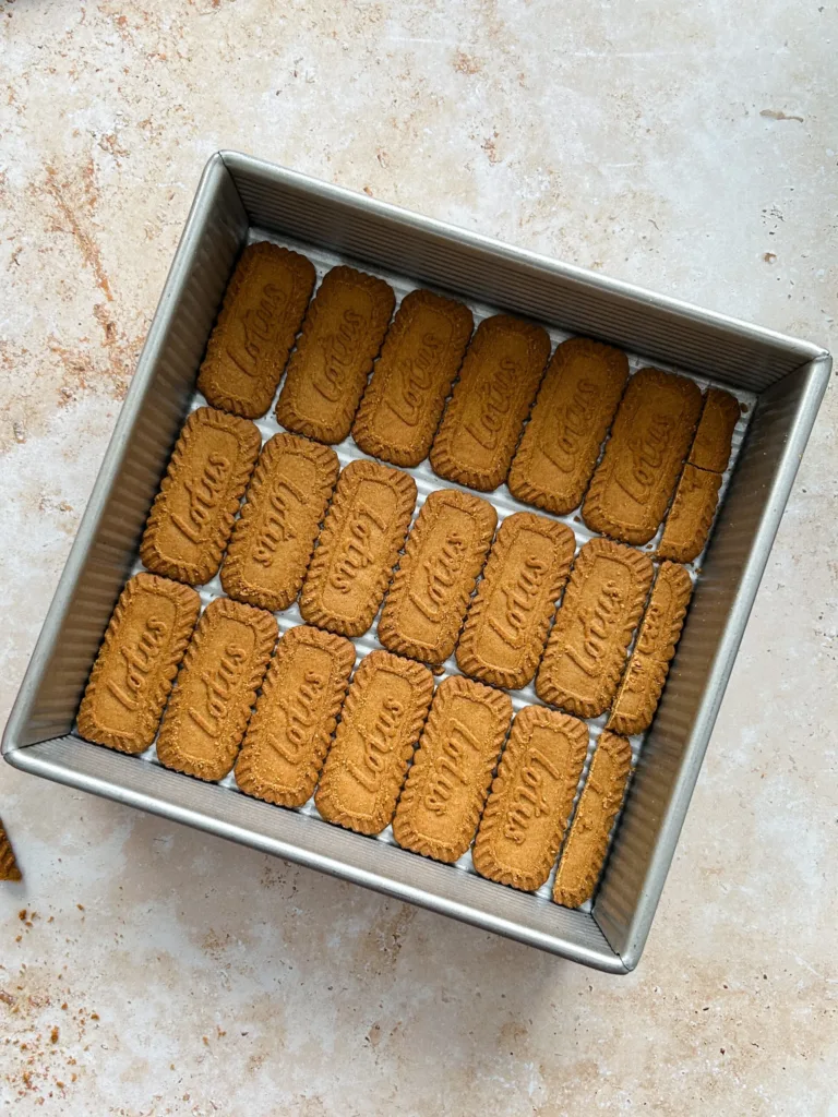 Arrange a layer of Biscoff cookies at the bottom, then spread a portion of the whipped cream evenly over them and top generously with mango pieces.