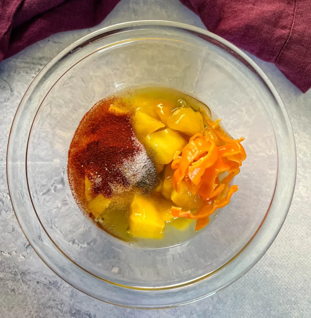 Add the diced mango, chopped habaneros, lime juice, vinegar, honey, smoked paprika, garlic powder, onion powder, salt, and pepper to a bowl or blender container.