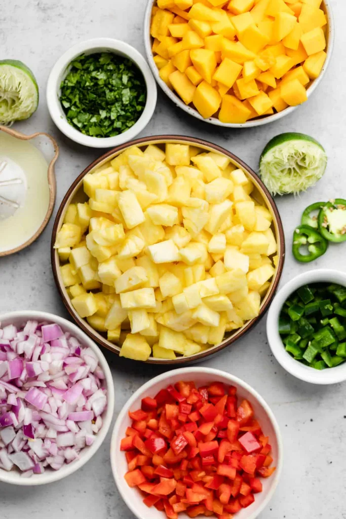 Chop the pineapple, mangoes, red pepper, jalapeño, and red onion into small, bite-sized pieces so everything mixes evenly and is easy to scoop.